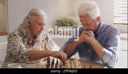 Playing against the chess master. a senior couple sitting together and playing chess in the kitchen at home. Stock Photo