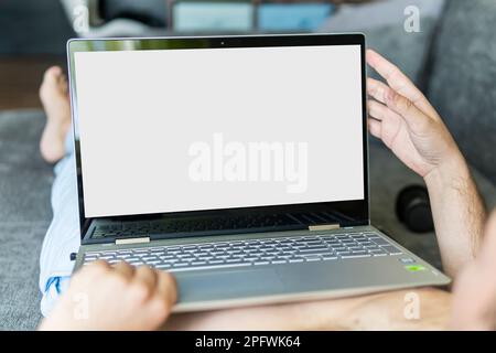 Closeup image of man lying on a bed working on laptop computer. POV shot of man relaxing in bedroom using touch screen computer. Copy space. The space Stock Photo