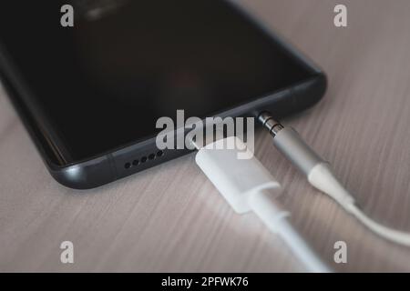 USB Type-C port, 3.5 headphone jack and screen on smartphone. Macro. Modern technologies. Connection 3.5 mm audio jack to a black mobile phone. Stock Photo