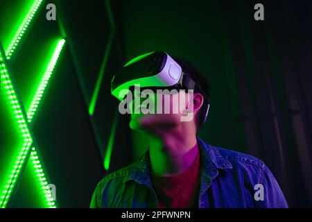 Man watching objects in virtual reality with a smile on his face. Tech-savvy young man experiencing an exciting game using VR goggles, immersing himse Stock Photo