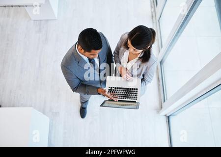 A high performing team needs high performing technology. High angle shot of a young businessman and businesswoman using a laptop in a modern office. Stock Photo