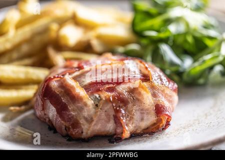 Juicy and crispy round cheese and bacon wrap served with fries and salad on the side. Stock Photo