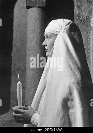 A young nun pictured from the side holding a candle. Sweden 1950 Stock Photo