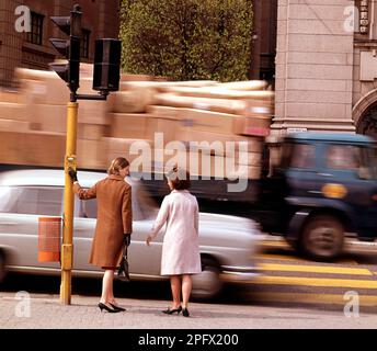 In the 1960s. A moment when women on a Stockholm street are standing waiting to cross the street when the lights turn green. A car and a lorry is seen passing in speed. Sweden 1967 Stock Photo