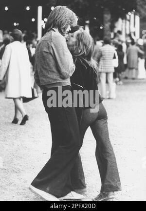 Kissing in the 1970s. A young couple at an outdoor dance event visibly attracted to each other close to kissing. They are dressed in the typical wide legged trousers that were a fashion in this 1970s decade. Sweden 1972 Stock Photo