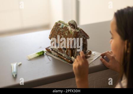 A girl plays with a gingerbread house for traditional Christmas decoration Stock Photo