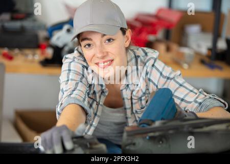 female mechanic uses power tool in the workshop Stock Photo