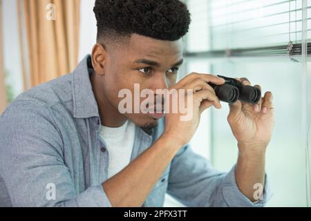 handsome man with binoculars on grey background Stock Photo