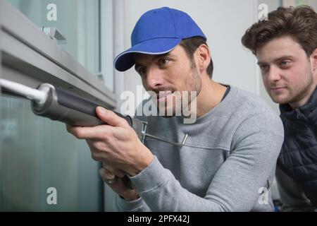 handyman using sealant gun on window Stock Photo