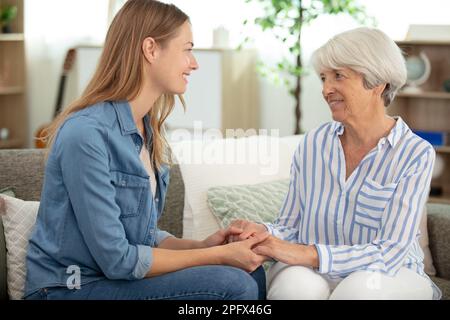 cheerful old mother and young adult woman talking laughing together Stock Photo