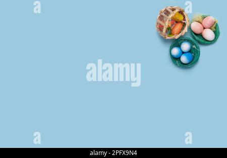 A charming Easter-themed pastel blue background showcasing three decorative baskets with colorful Easter eggs and an adorable chick in the upper right Stock Photo