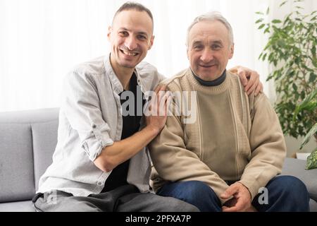 Happy two generations male family old senior mature father and smiling young adult grown son enjoying talking chatting bonding relaxing having Stock Photo