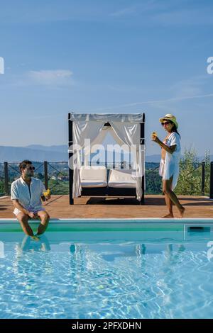 Luxury country house with swimming pool in Italy. Couple on Vacation at a luxury villa in Italy, men and woman watching the sunset. and drinking cocktails Stock Photo