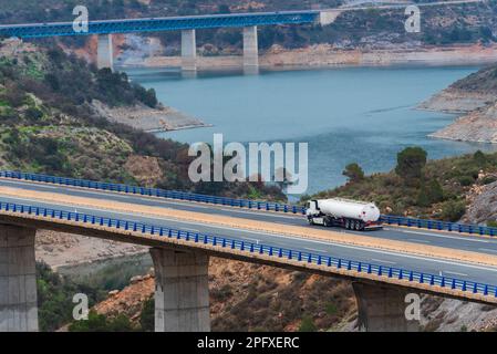 Tanker truck with dangerous goods plates driving through a viaduct over a swamp. Stock Photo