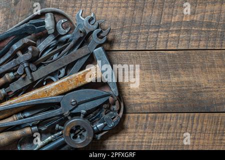Vintage tools displayed in a old metal tray on a wooden board background, close up, top view, copy space. Dirty set old working tools Stock Photo