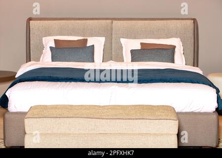 Double bed with a soft fabric headboard in beige tones and a blue velor duvet. Stock Photo