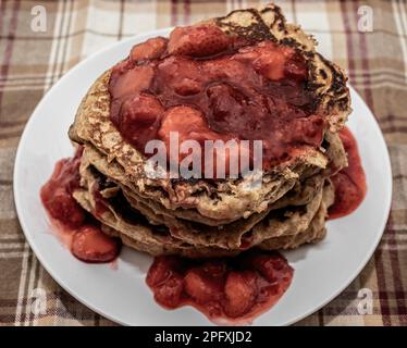 Whole grain buttermilk pancakes topped with strawberry sauce on a plaid tablecloth in Taylors Falls, Minnesota USA. Stock Photo