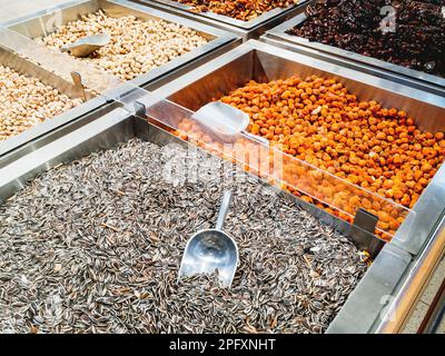 Boxes with sunflower seeds, dried fruits and nuts. A special scoop for sprinkling grits in packages. The display in the store. Stock Photo
