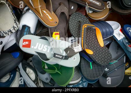 Plastic flip-flops, sliders and sandals, including fake Nike and Adidas, for sale in a shoe shop in Dalat, Vietnam. Stock Photo