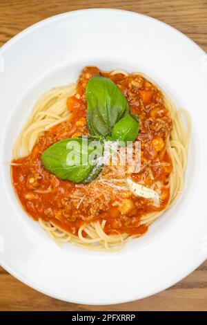 homemade spaghetti bolognese with minced meat with juicy green basil, parmesan cheese, carrot pieces and butter shavings Stock Photo