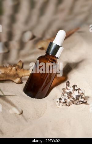 Summer sunscreen essence on sand background with seashells and starfish. Beach holiday cosmetics. Stock Photo