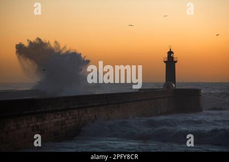 Big wave at the lighthouse against the background of the sunset. Atlantic, Portugal. Stock Photo