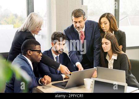 Group of multiracial businesspeople pointing at laptop screen and discussing data during work in office Stock Photo