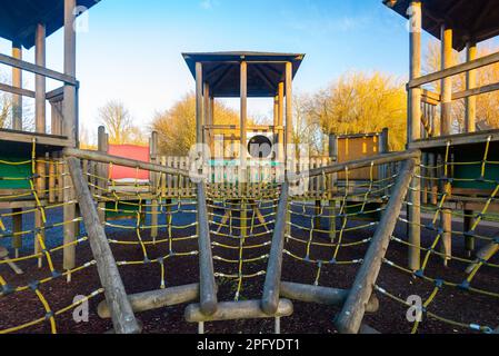 Close up of children's playground wooden play structure fort with climbing ropes, ladder and bridge. Stock Photo