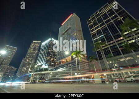 Downtown district of of Miami Brickell in Florida, USA. Brightly illuminated high skyscraper buildings and street with car trails and metrorail Stock Photo
