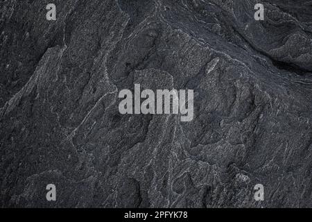 Close-up of a unique and beautiful rock surface, front view. Abstract full frame natural textured dark background in black and white. Stock Photo