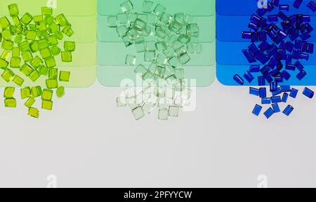 multicolored transparent plastic granulates with its color samples plates on white Stock Photo