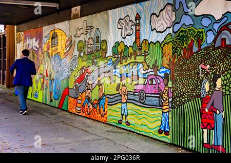 A man in a suit walks past a colorful mural on Dauphin Street, March 8, 2023, in Mobile, Alabama. Stock Photo