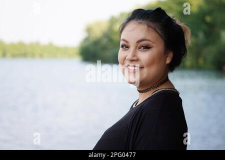 happy young asian woman standing at lakeside Stock Photo