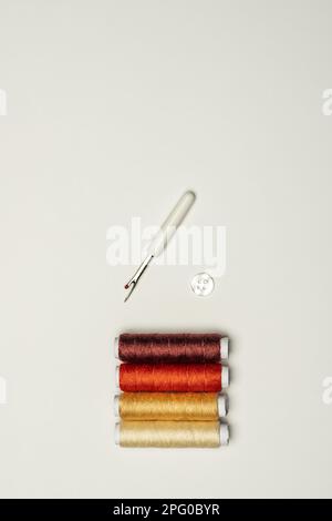 still life with spools of thread of various colors, a white button and a sewing utensil Stock Photo