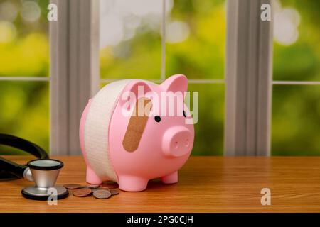 Piggy bank with bandage and stethoscope. Health care costs, medical debit and financial health concept. Stock Photo