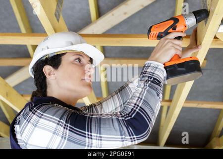 female builder using cordless drill overhead Stock Photo