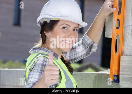 female builder using spirit level outdoors Stock Photo