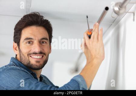 young man installing curtains over window Stock Photo