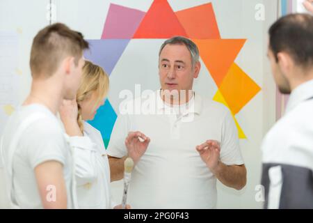 instructor showing apprentices how to paint Stock Photo