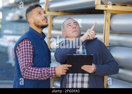 two workers in hardhats at plant checking parameters of pressure Stock Photo