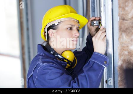 workwoman is checking dimensions of finished metal window Stock Photo
