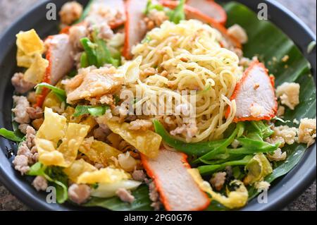 yellow noodles Thai food - dried noodles food on plate with condiment minced pork lemon lime peanuts dumpling red pork on plate Stock Photo