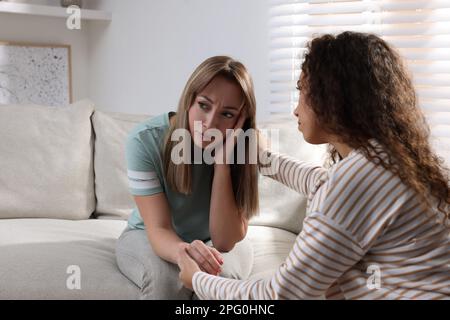 Unhappy young woman having session with her therapist indoors Stock Photo
