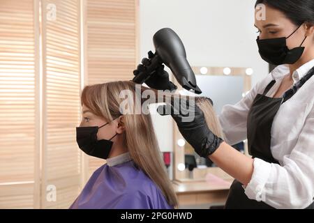 Professional stylist working with client in beauty salon. Hairdressing services during Coronavirus quarantine Stock Photo