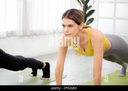 Young woman and man practicing workout with posing plank on mat while motivation and determined at home, female and male doing weight training with st Stock Photo