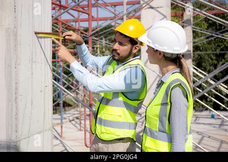 Engineer young man and woman using tape measure for check and examining length of structure at construction site, architect or contractor inspection a Stock Photo