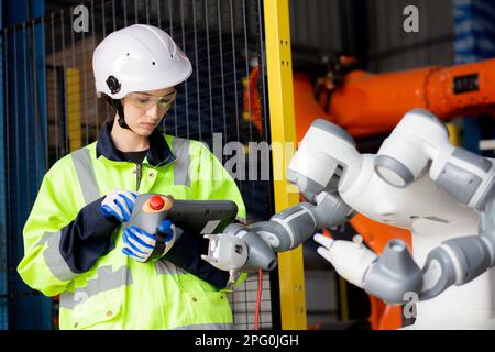 Young engineer woman checking and maintenance machine robot arms technology intelligence and innovation at factory industrial, people or technician ex Stock Photo