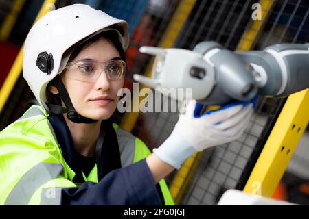 Young engineer woman checking and maintenance machine robot arms technology intelligence and innovation at factory industrial, people or technician ex Stock Photo