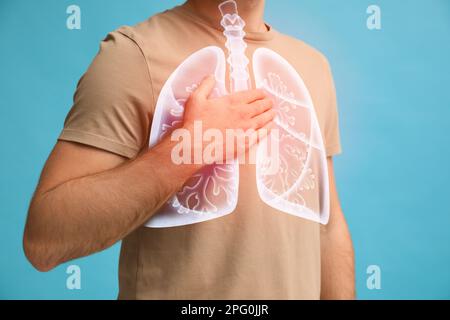 Man holding hand near chest with illustration of lungs on turquoise background, closeup Stock Photo