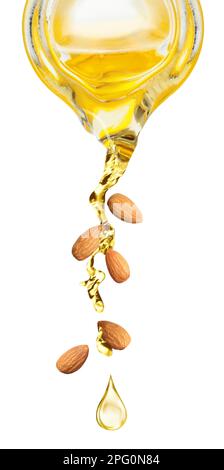 Pouring organic almond oil from glass pitcher and falling nuts on white background. Vertical banner design Stock Photo